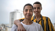 Two people smile standing in front of their apartment building.