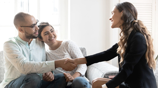 A multiracial couple shakes hands with a TD employee after signing personal loan documents.