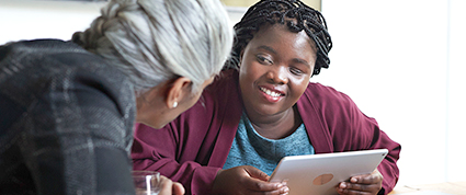 A female TD colleague with grey hair meets with a female customer with a visual impairment.