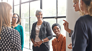 A diverse group of women meet to discuss business and community support.