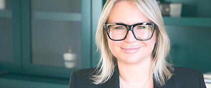 Eva Hartling wears a black business suit and smiles at the camera.