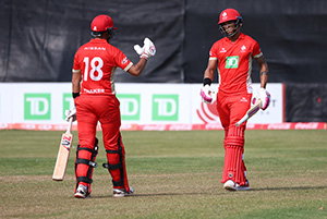 Deux hommes vêtus d’une tenue de cricket sont sur un terrain de cricket